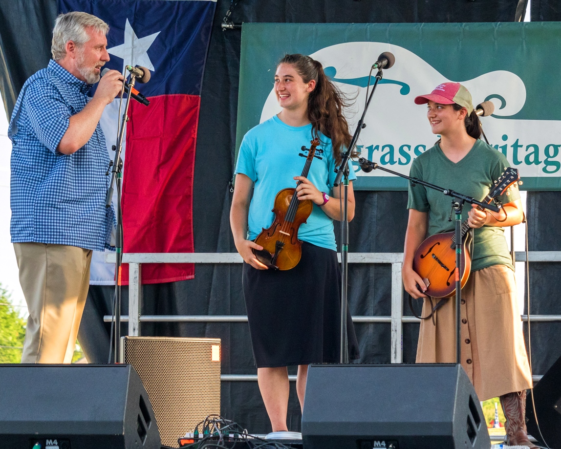 Alan Tompkins presents Play it Forward! instruments to Hannah B and Sarah B at Wylie Jubilee 2024. ©Nate Dalzell