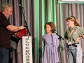 Celia L gets her new fiddle on stage with Jessica Tompkins assisting (2022 © Jim Gerber )