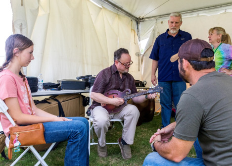 Jesse Brock sets up Emma M's new mandolin backstage at Wylie Jubilee 2025