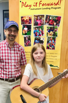 Teacher Fred Gebhardt presents Play it Forward! guitar to Kinley B!